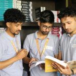 Three male students studying in a library, focused on business books, at Nepal university.